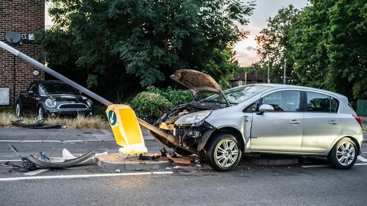 Silver hatchback with a smashed front end after hitting a street bollard, the kind of damage that triggers a write off category.