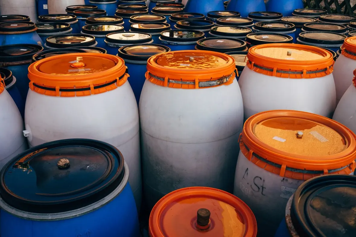 Rows of sealed industrial plastic drums in outdoor storage, the kind of substances a COSHH assessment must record and control.