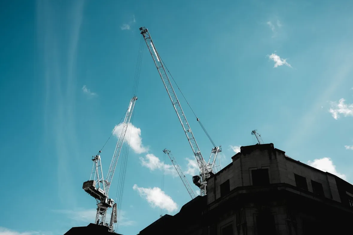 Two luffing jib tower cranes above a stone city building, the lifting equipment LOLER thorough examination records must cover.