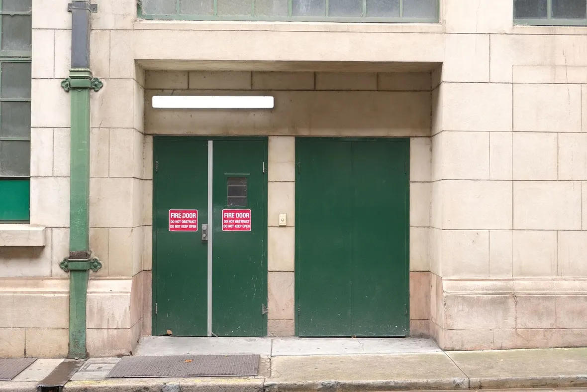 Green double doors carrying red fire door do not obstruct signs, with hinges, vision panel and closing gear checked at every inspection.