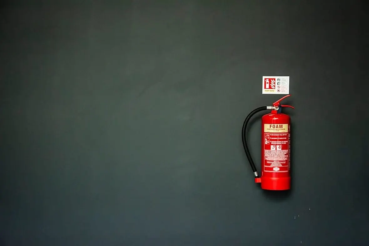 A row of UK fire extinguishers, BS 5306 sets annual servicing, extended service, and replacement intervals.
