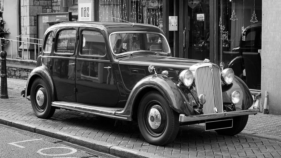 A vintage black saloon car with a chrome slatted grille parked at a kerb, the kind of pre-war vehicle DVLA historic registration records cover.