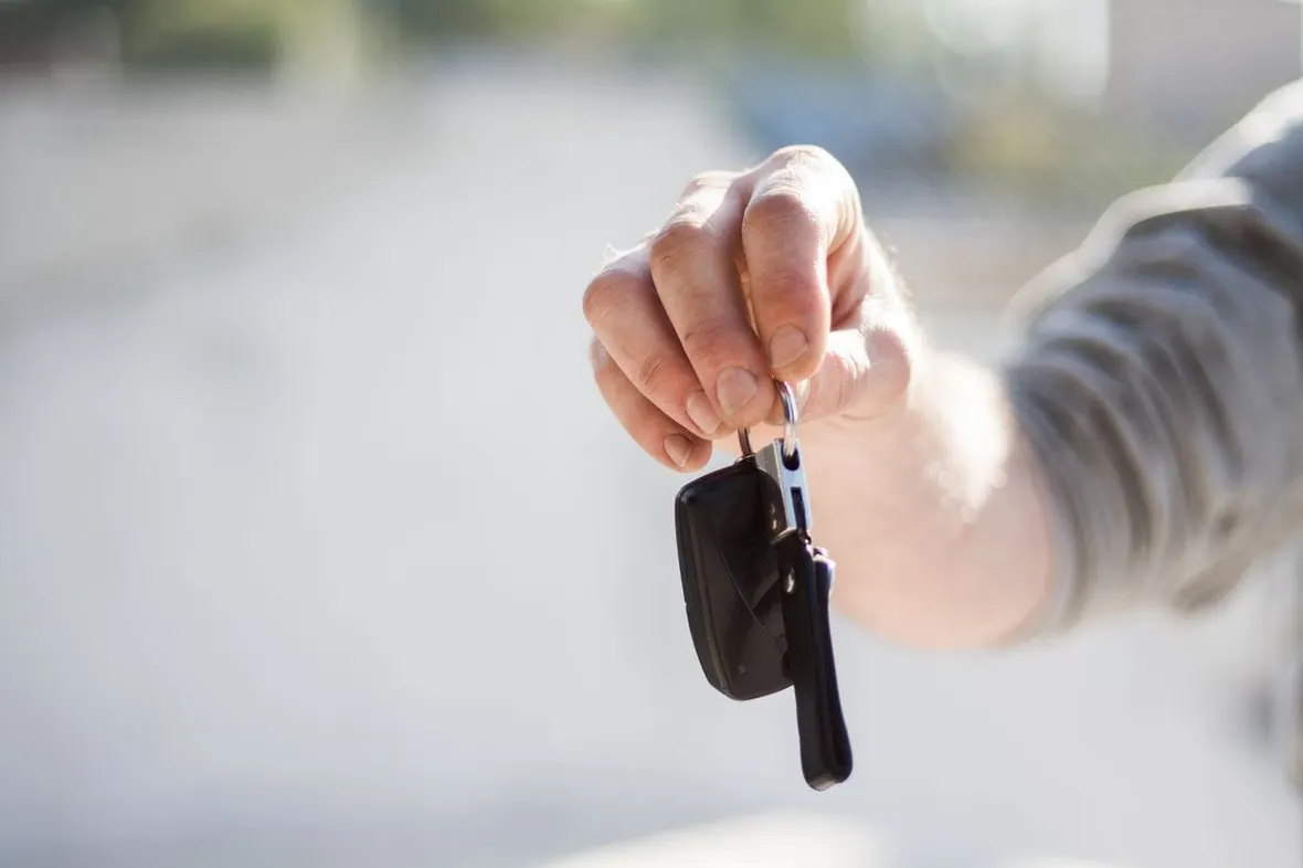 A hand holding out a set of car keys, check the V5C logbook against the vehicle before any money changes hands.