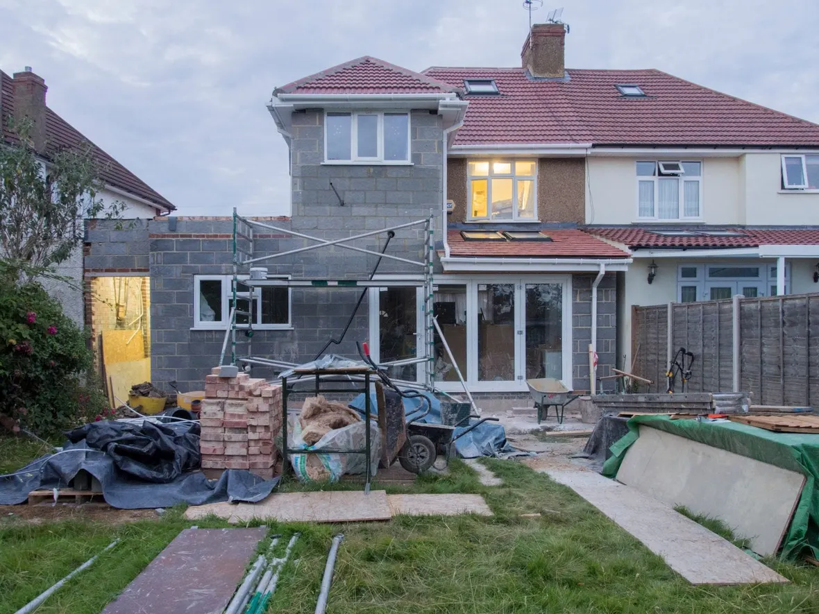 Rear extension under construction on a British semi detached house with blockwork walls and a new tiled roof, the kind of work needing planning records.