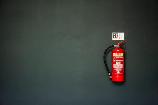 A row of UK fire extinguishers — BS 5306 sets annual servicing, extended service, and replacement intervals.