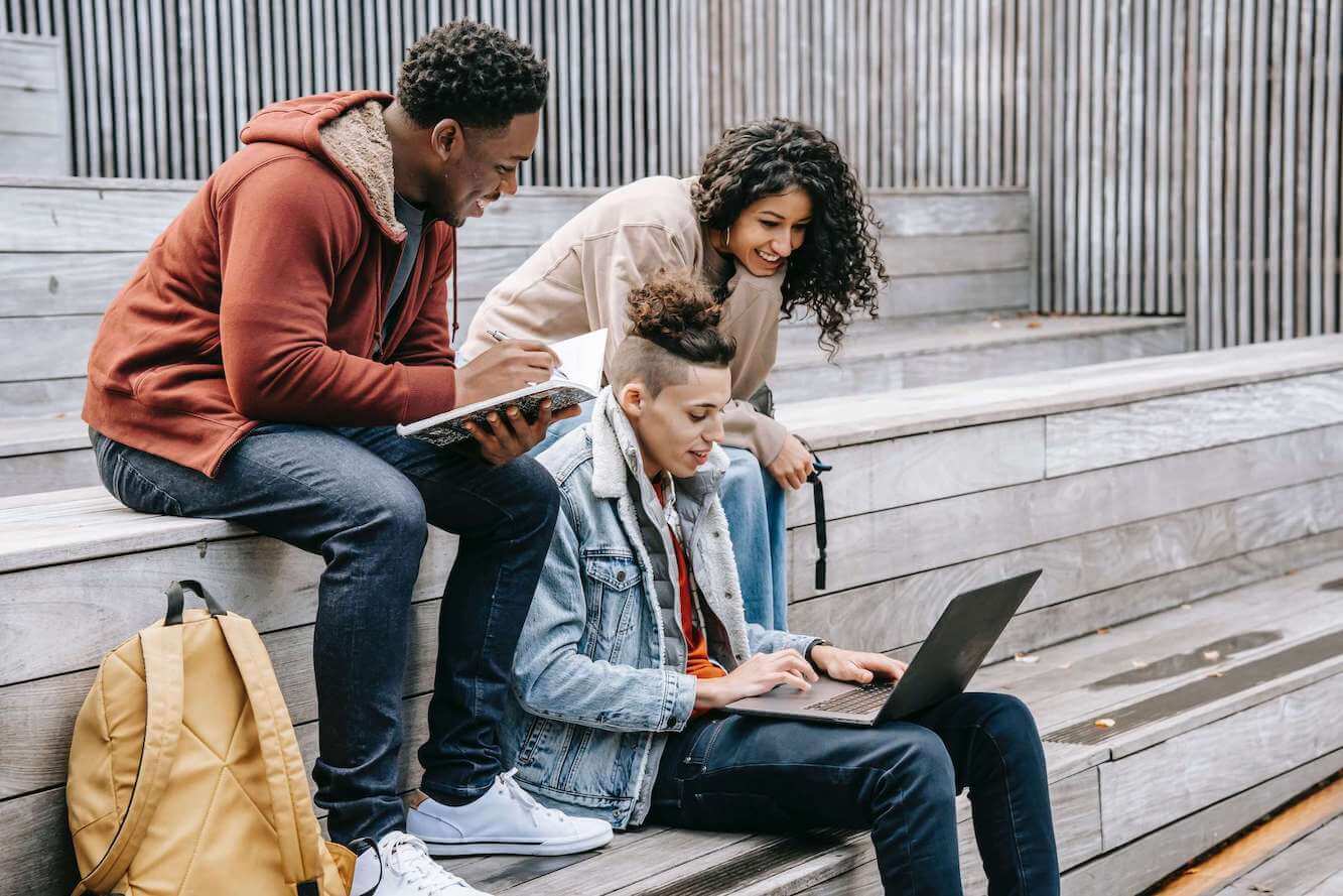 Three students pictured studying outside.