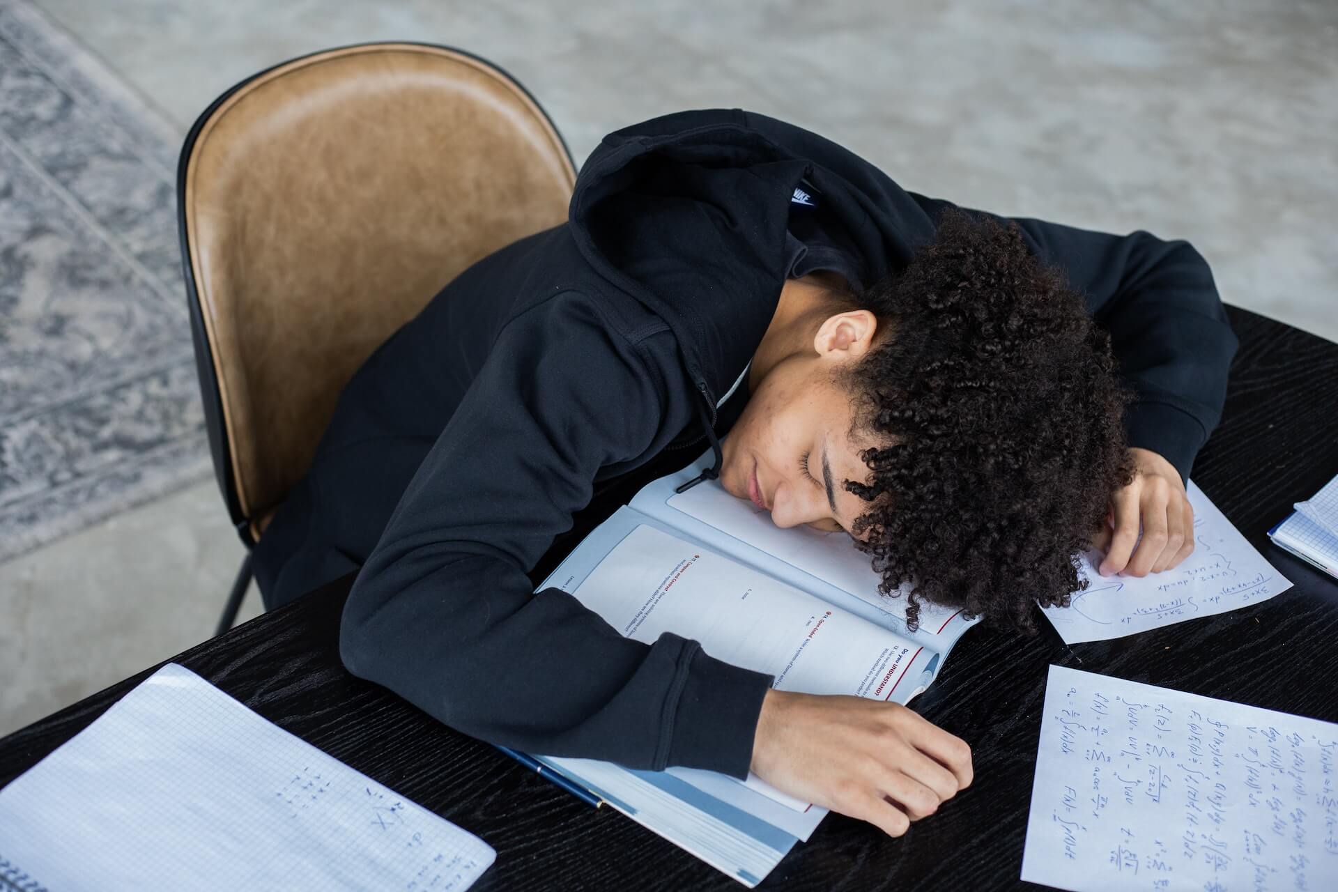 Stressed student resting his head on his text book