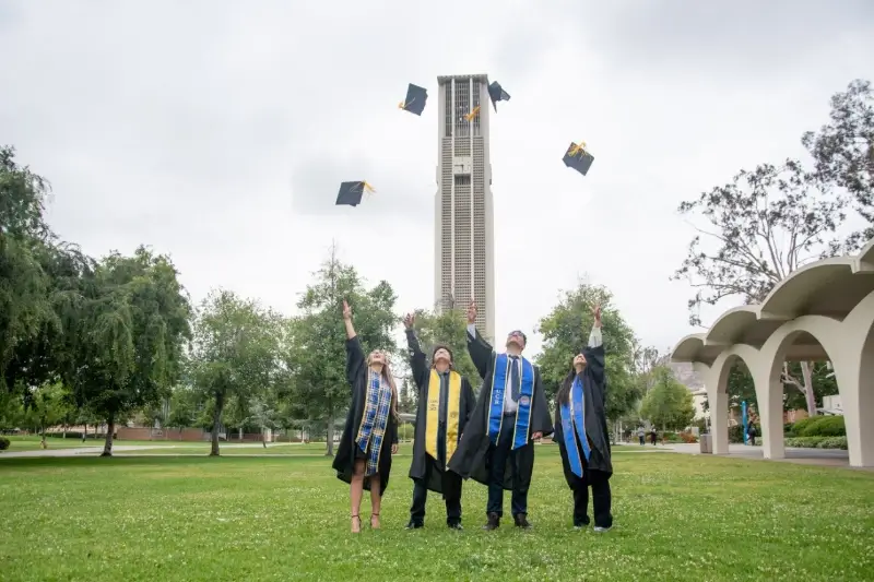 four students toss their caps in the air at graduation