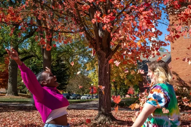 two high school seniors frolic in fall foliage