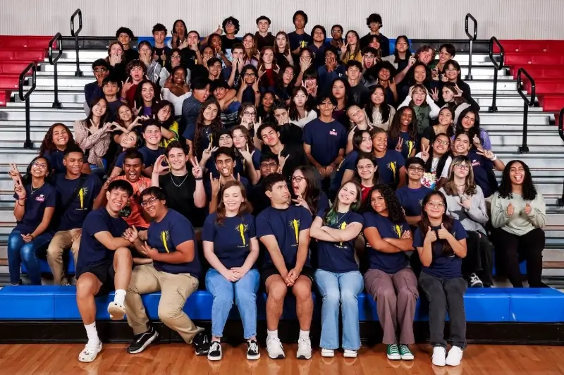 class of students sit on the bleachers