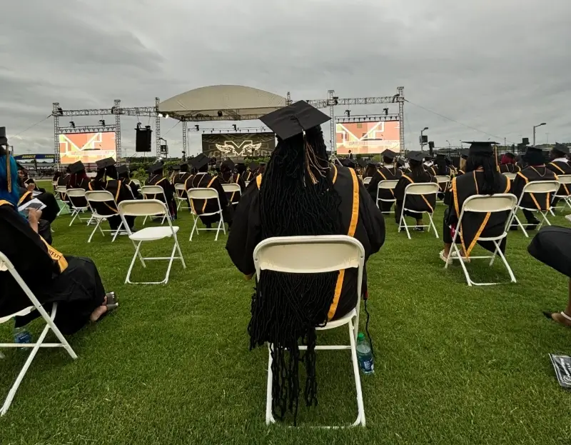 students sit in chairs on school lawn for graduation