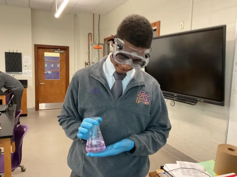 aspiring biology major holds beaker filled with violet liquid