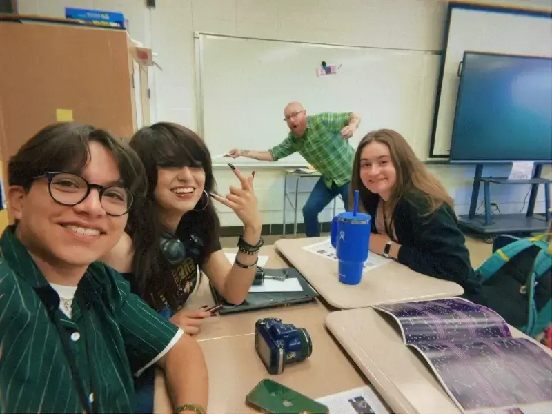 professor poses with students in math classroom