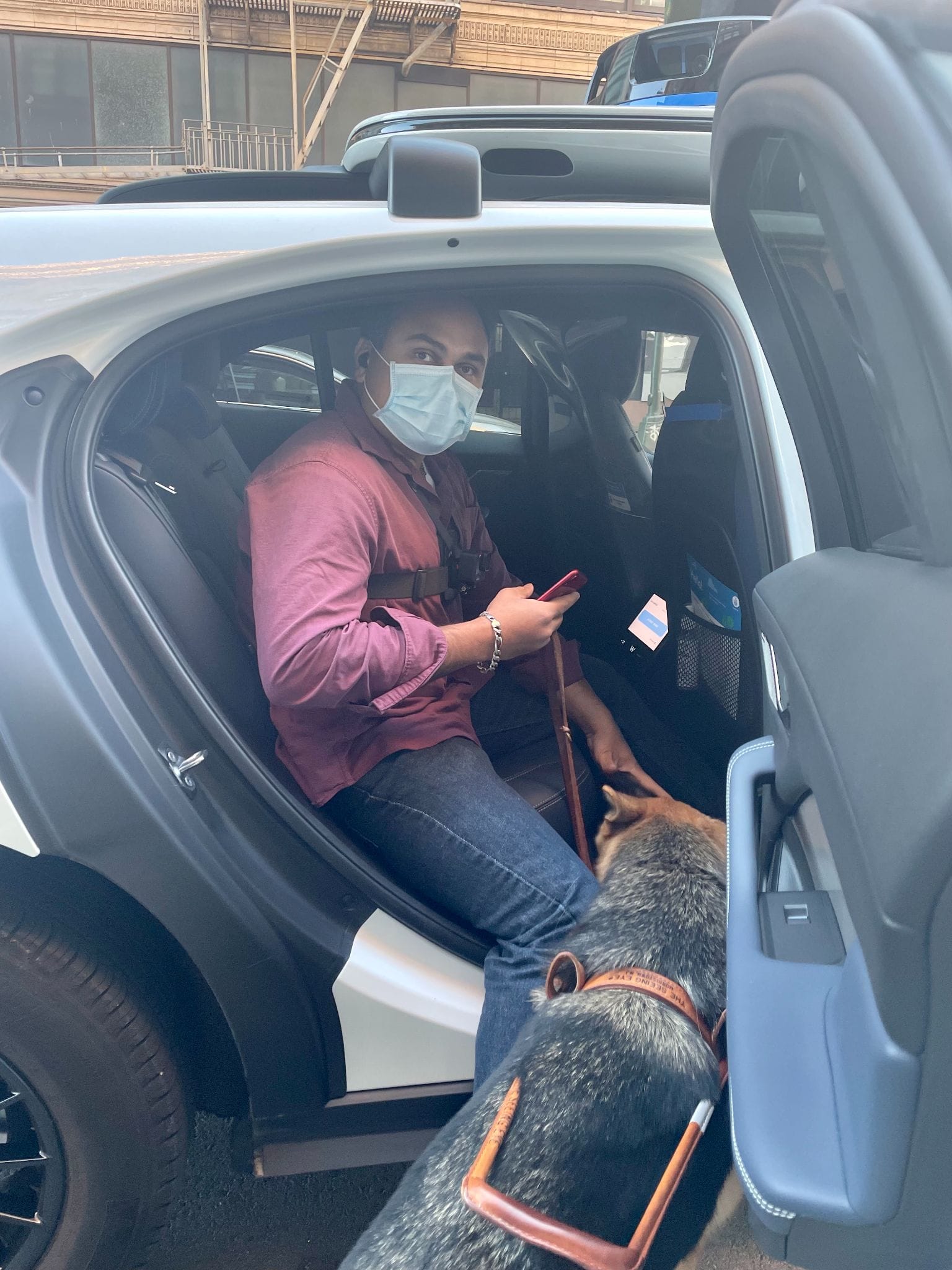 A participant seated in the back of a Waymo vehicle, seen through the open door.