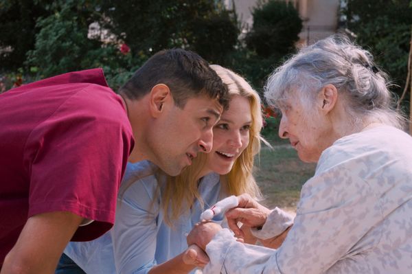 Marie-Lou and another carer, holding the hands of an elderly resident, supporting her on her walk.
