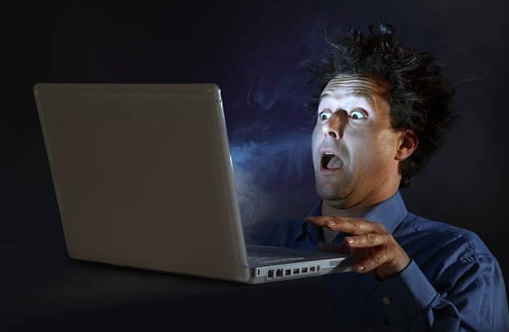 Stock photo of a man getting scared of a glowing computer screen.