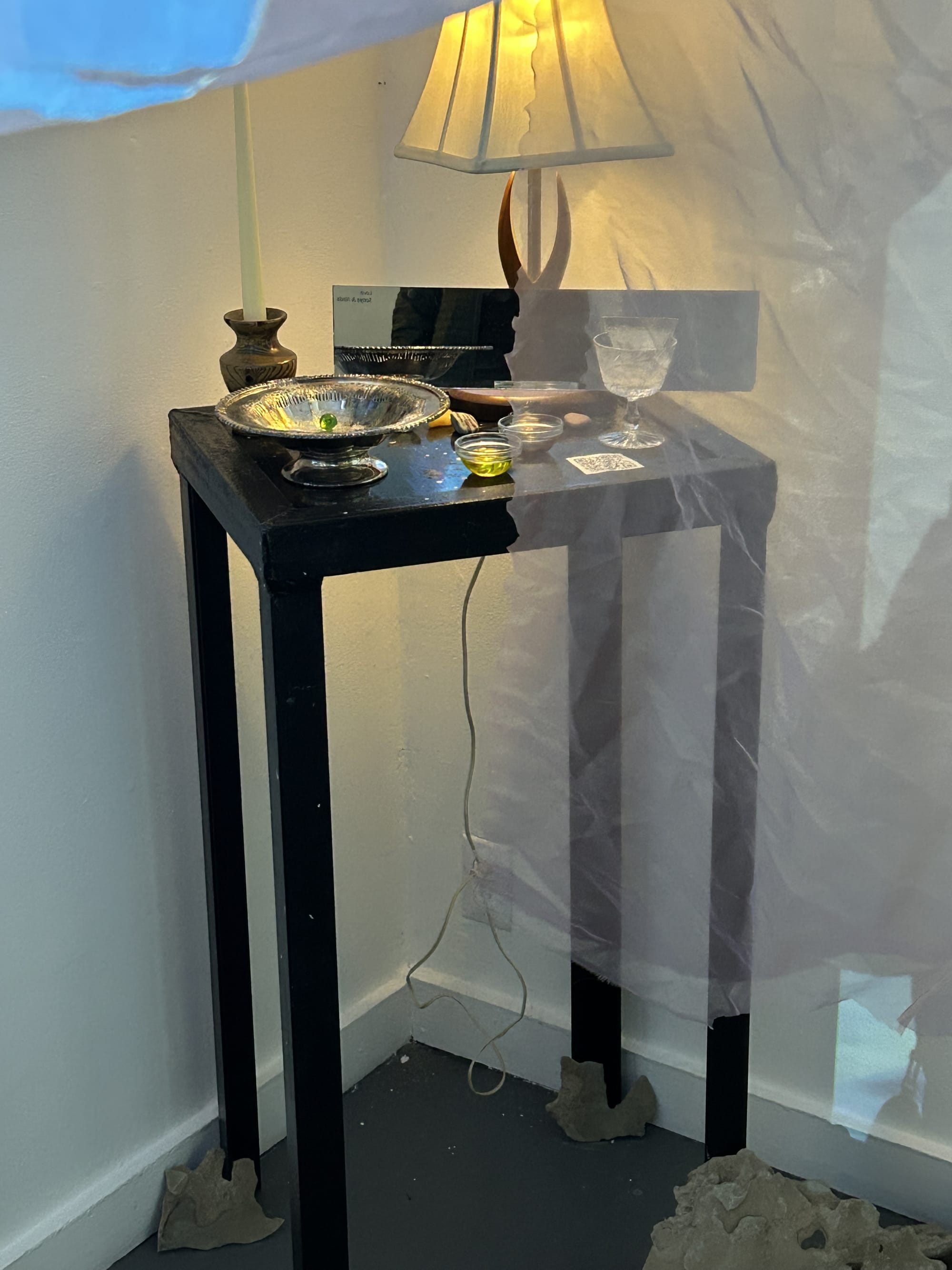 A nightstand set with a metal bowl for keys and other personal items like a candle and lamp. 