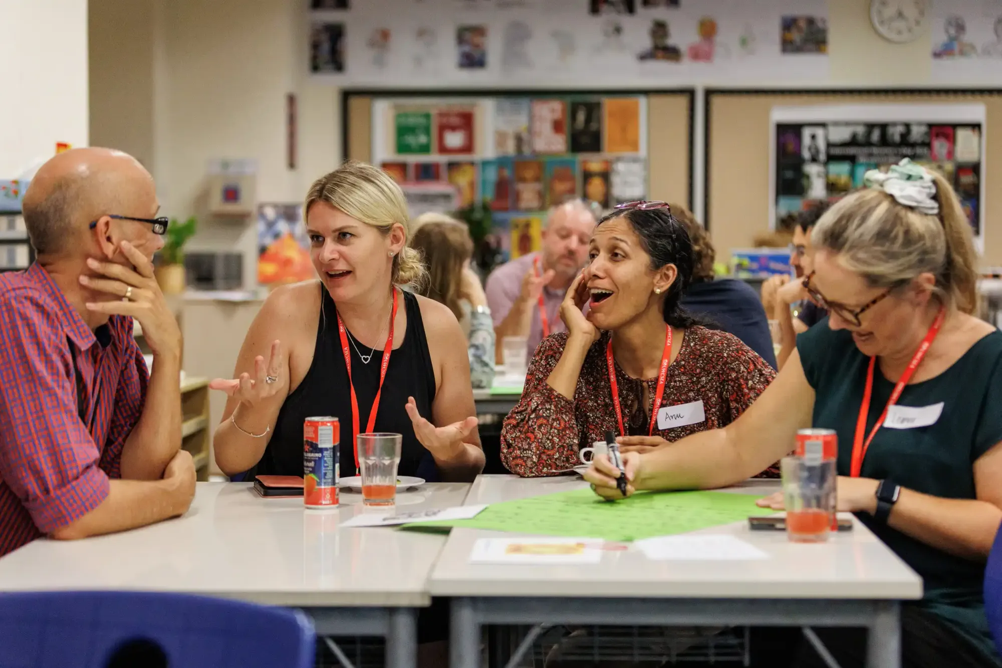 Teachers and staff seated around a table in animated conversation, engaging in collaborative discussion.