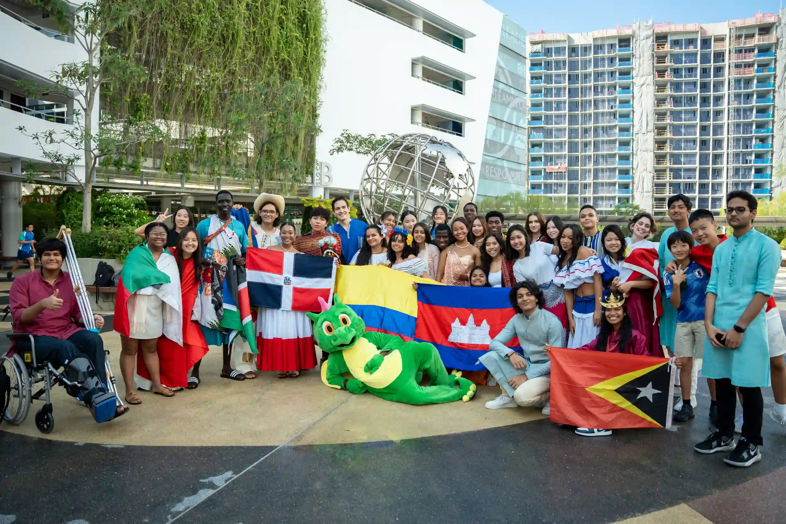 Group of students in national attire holding international flags at UWCSEA’s cultural celebration.