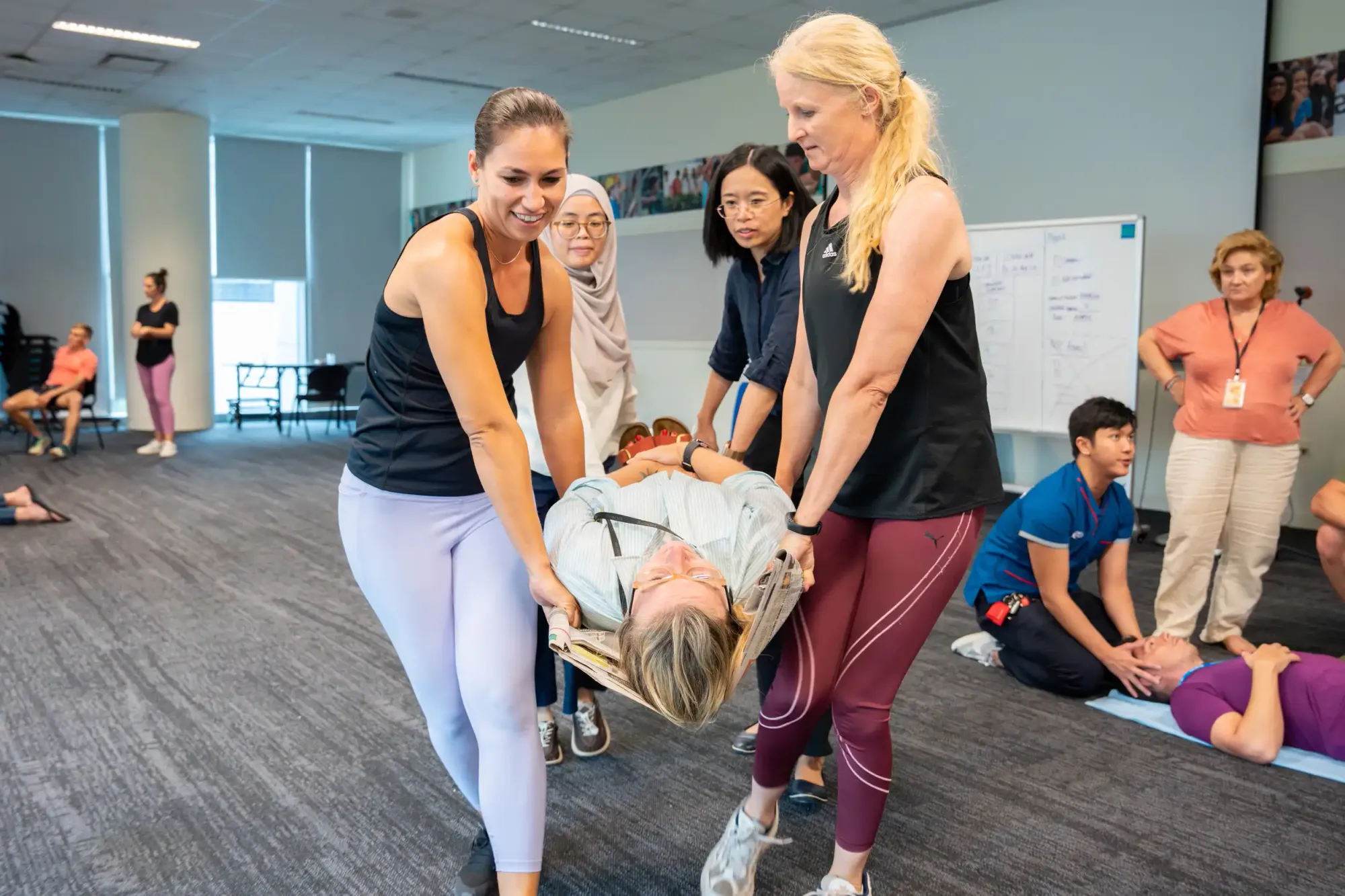 Staff practicing emergency first-aid by carrying a colleague during a training session.