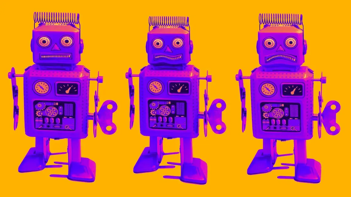 Three retro purple wind-up toy robots lined up against a bright orange background.