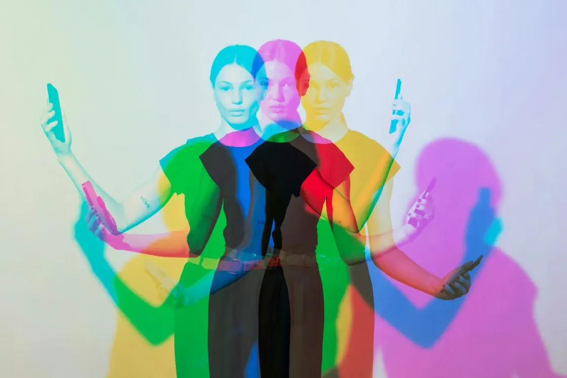 Multiple colour overlays of the same person holding a phone, creating a layered effect