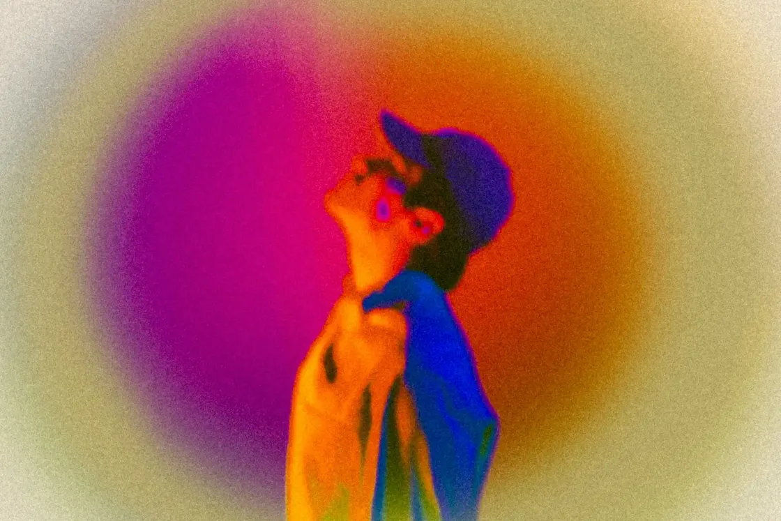 Portrait of a young person in a cap looking upward, in vivid warm and cool tones, representing the aspirational and scrutinising perspective of Gen Z candidates evaluating employer brands.