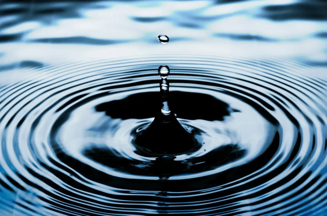 A close-up image of a water droplet striking a dark blue surface and sending concentric ripples outward, symbolising the expanding influence of an employee value proposition.