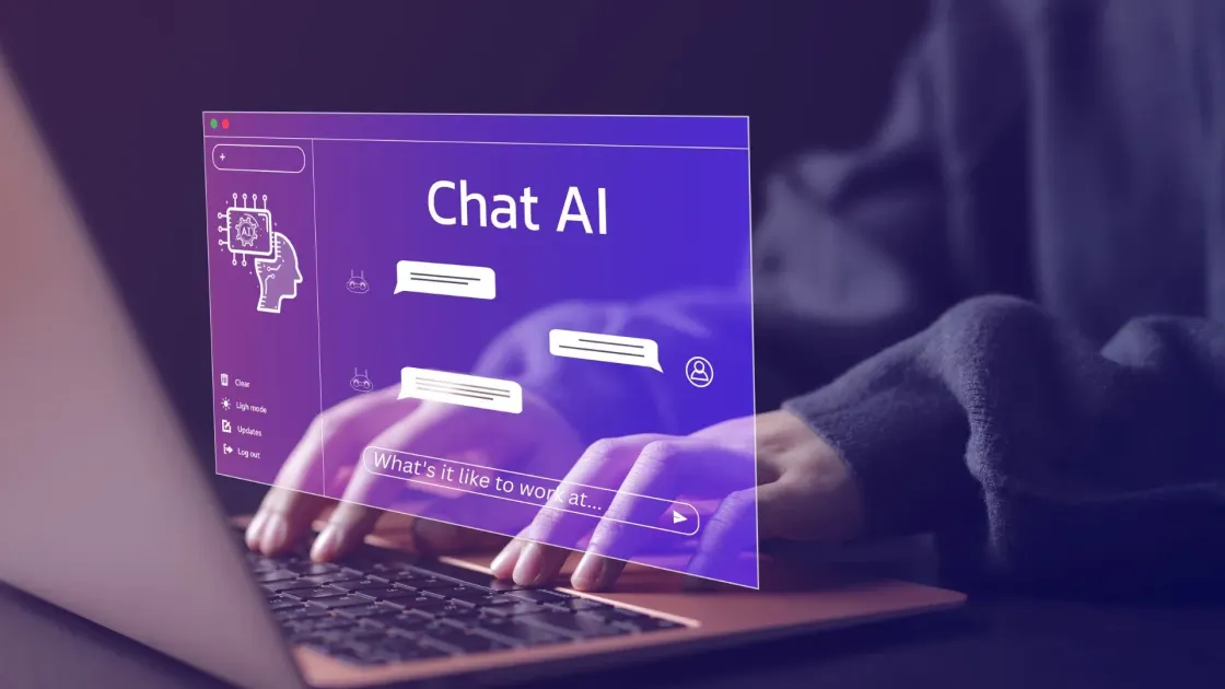 Hands typing on a laptop with an AI chat interface overlay showing the prompt "What's it like to work at..." representing how candidates now research employers through AI tools.