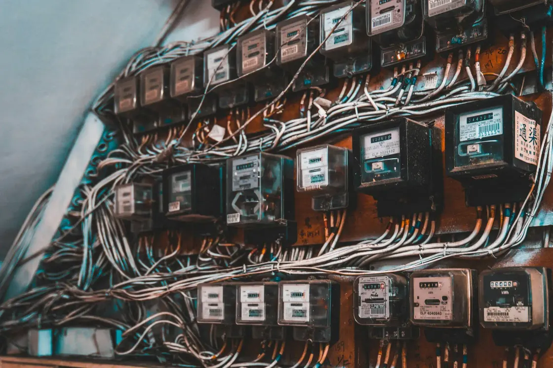 Wall of independent electricity meters tangled in cabling, each ticking on its own consumption.