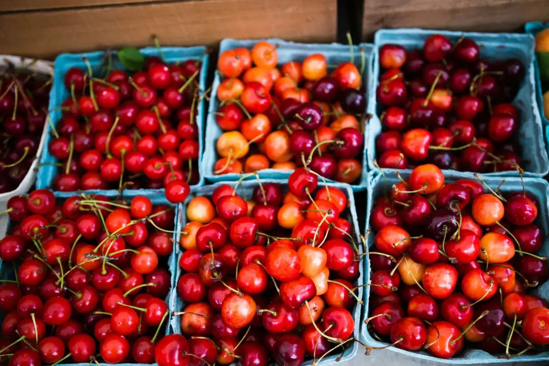 Punnets of fresh cherries on a wooden market stall, illustrating cherry-picking in job recommendations.