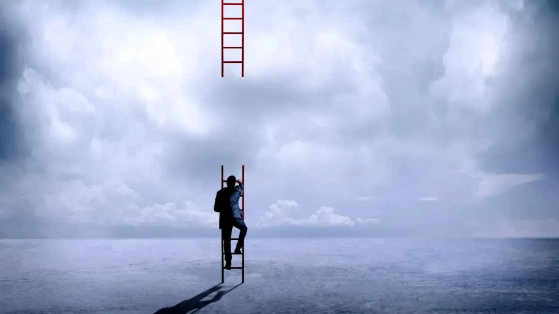 A person in a suit climbing a red ladder toward a second ladder that stops short in the clouds, symbolising a broken career ladder and a narrowing path upward.