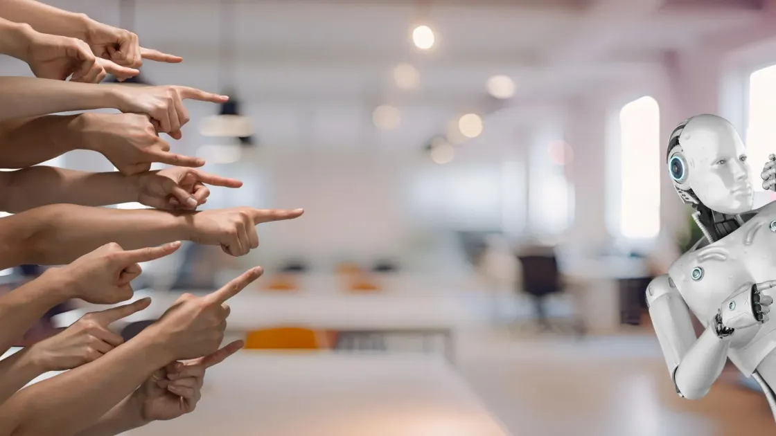 Office workers pointing fingers at a humanoid AI robot, illustrating employer blame for AI-driven layoffs, September 2026