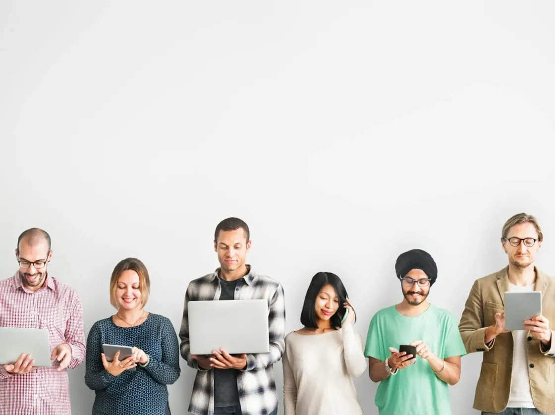 Employees on their phones and laptops, part of the workforce building visibility through personal posting and self-promotion.