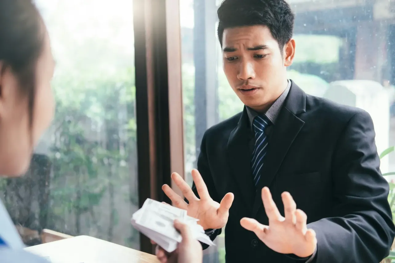 Concerned businessman in suit pushes back against cash offer, embodying mission-first talent retention.