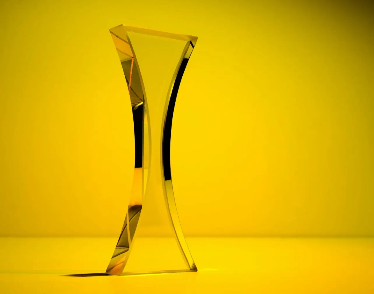 A single, modern-looking glass trophy set against a vibrant yellow background, symbolizing excellence and innovation in employer branding.