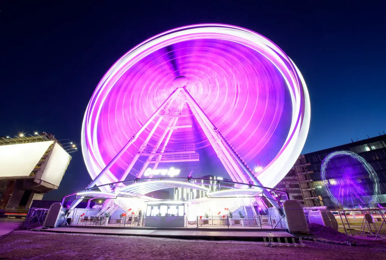 Ferris wheel spinning in bright purple light at night, symbolizing motion without progress and the illusion of employer branding ROI.