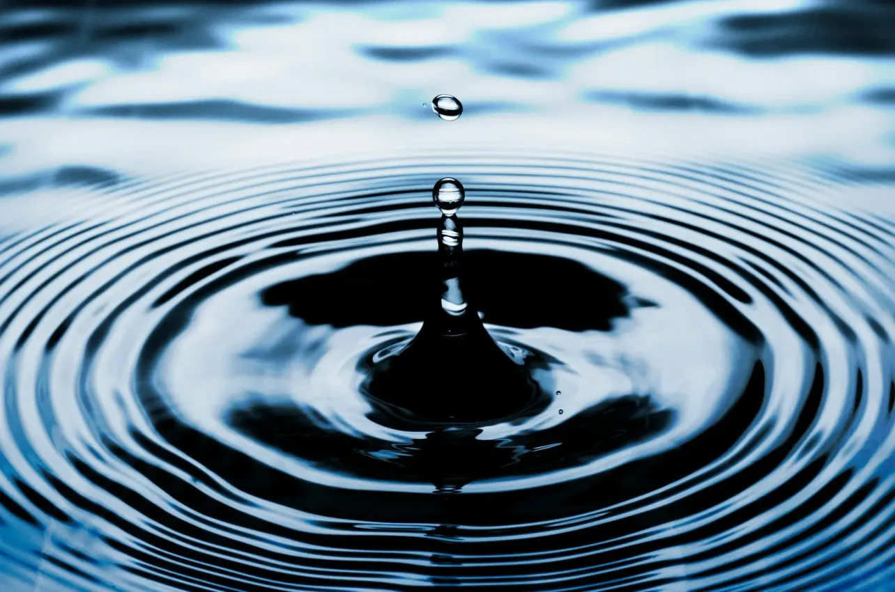 A close-up image of a water droplet striking a dark blue surface and sending concentric ripples outward, symbolising the expanding influence of an employee value proposition.