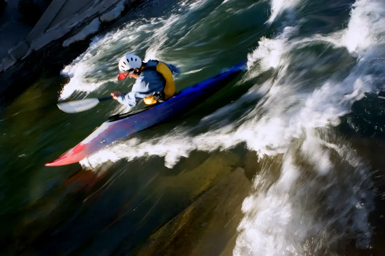 Senior engineer burnout in AI-forward organisations, illustrated by a kayaker paddling hard against fast-moving whitewater rapids.