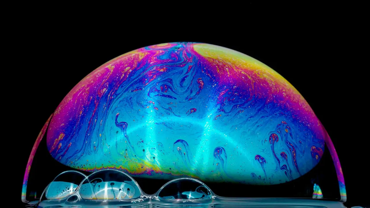 Iridescent bubble against a black background, illustrating the AI cost bubble and the pressure on employers as enterprise AI bills rise.