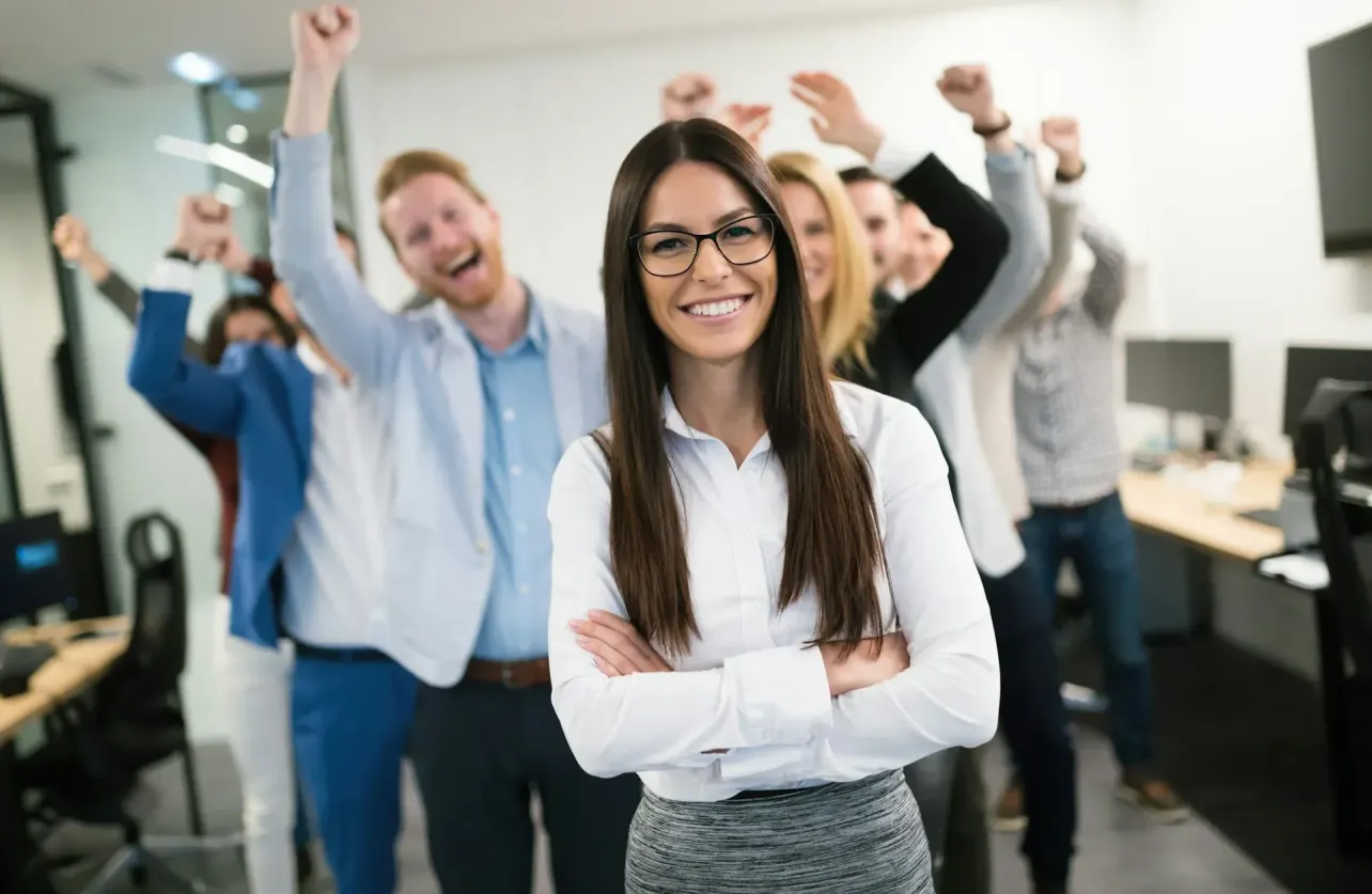Smiling employee standing in front of cheering colleagues in a polished office, illustrating an overly idealised employer brand and EVP.