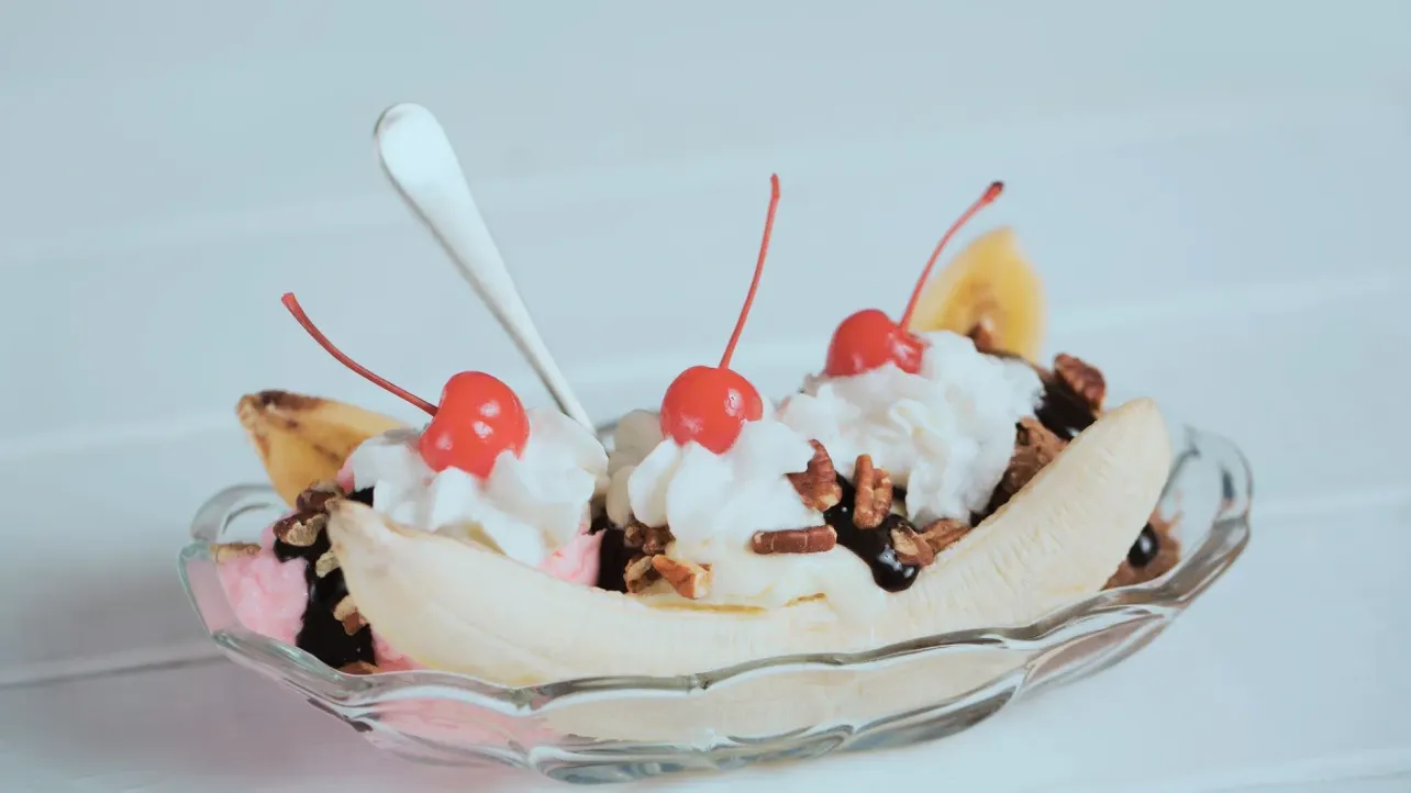 A banana split dessert with cherries and whipped cream, symbolising this week's conflicting employment and AI-layoff data.