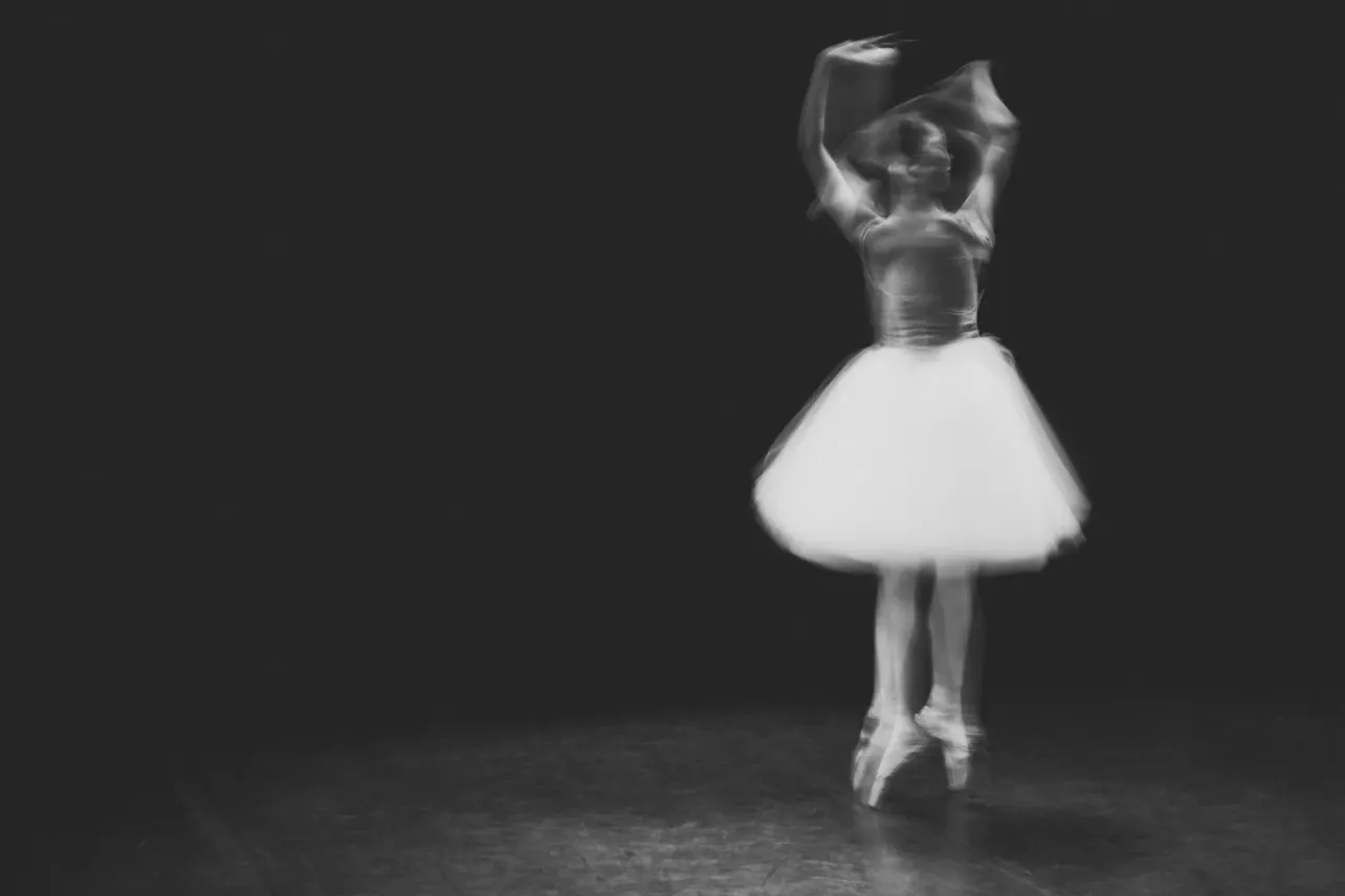 Ballerina mid-turn in motion blur on a dark stage, illustrating this week's Paper Cut on corporate turnaround language.