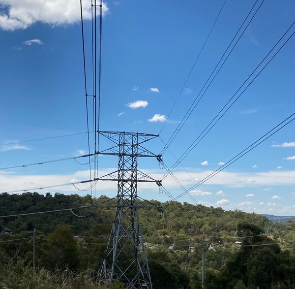 A power pylon on a mountainside, with powerlines going in different directions