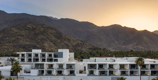 Exterior of the Thompson Palm Springs hotel with a view of the mountains in the distance.