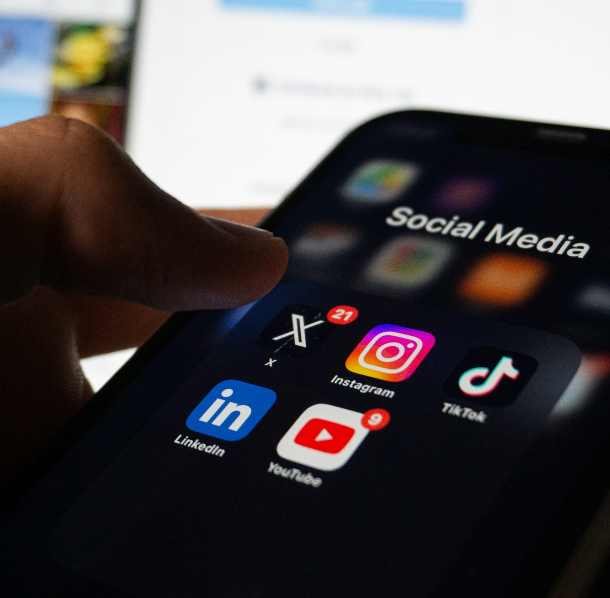 A person holding a smart phone with social media on the screen