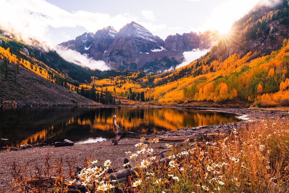 Classic photograph of the Maroon Bells during fall colors with a sunburst
