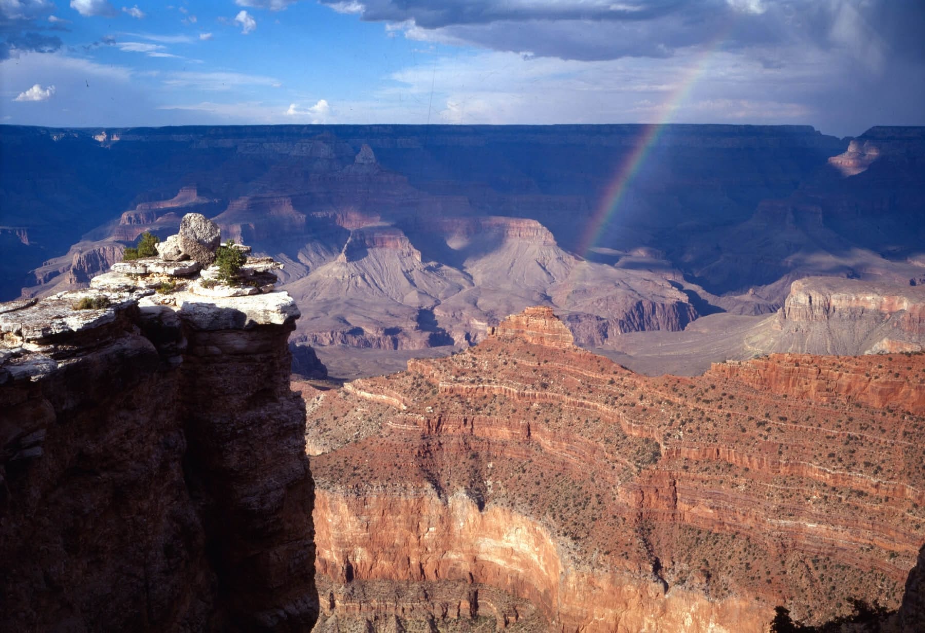 Rainbow arching over the Grand Canyon at Mather Point on the South Rim, with colorful canyon cliffs and expansive views from the accessible overlook.
