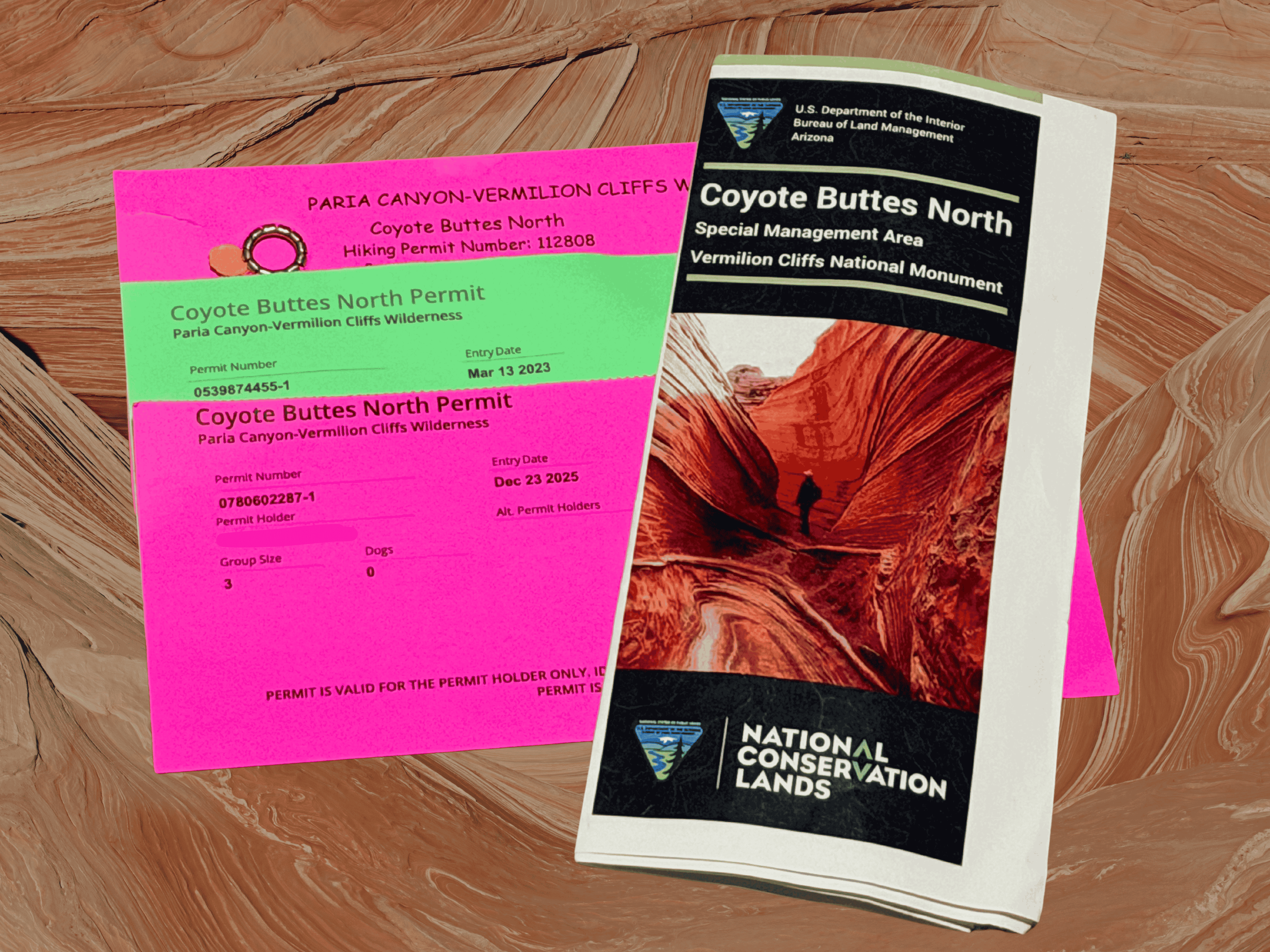 Three Coyote Buttes North hiking permits for The Wave in Arizona displayed alongside the BLM trifold photo navigation guide.