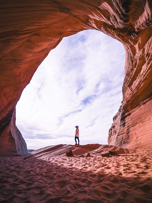 Interior view of Biidi the Arch, also known as the Secret Gas Station Sand Cave, showing curved sandstone walls framing the opening near Page, Arizona.